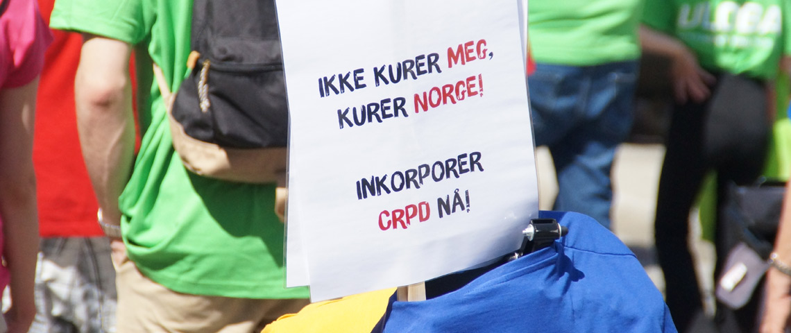 Plakat fra demonstrasjon med teksten "Ikke kurer meg, kurer Norge! Inkorporer CRPD nå!"