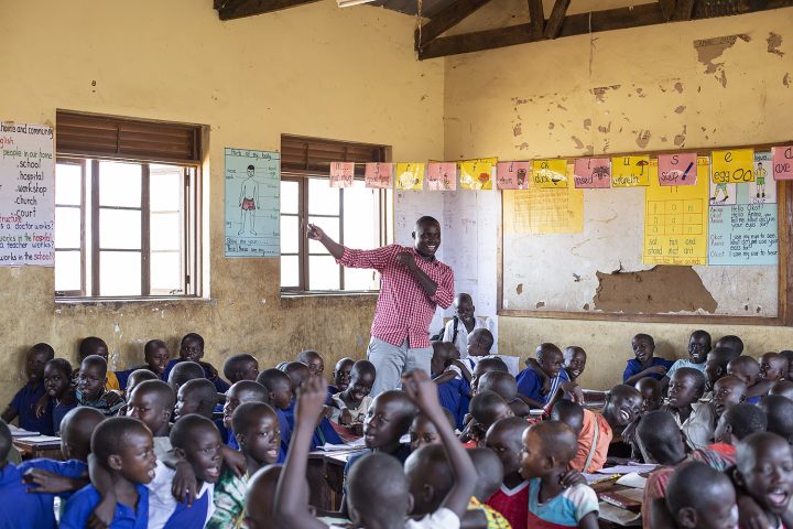 Unge barneskolebarn i Uganda synger en sang med læreren sin.