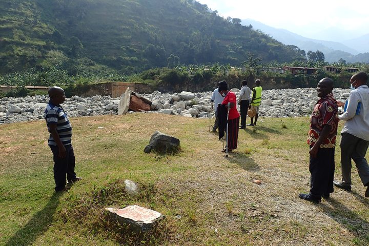 En gruppe mennesker er utendørs og ser på restene av en ødelagt bru i Uganda.