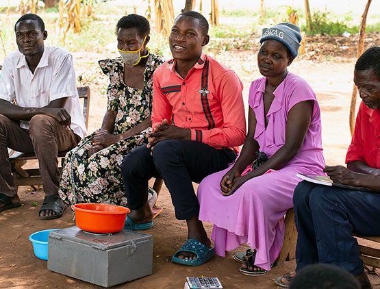 Fem melaninrike mennesker sitter ved siden av hverandre utendørs i Uganda