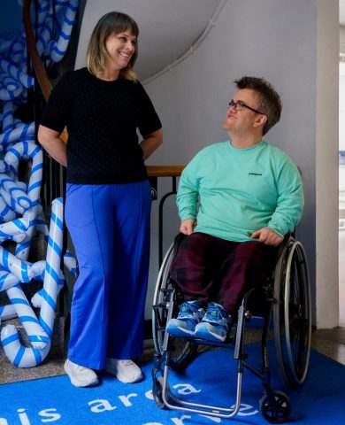 Vi ser kunstnerne i FAT, Anja Tveiterås og Fredrik Alden Thorsen. Thorsen sitter i rullestol, mens Tveiterås står ved siden av. Begge smiler.